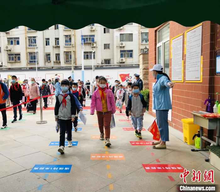 郑州市金水区金燕小学的小学生脚踩一米间隔线排队入校 杨晨 摄 河南多地小学今返校复学 校园教学活动渐入正轨